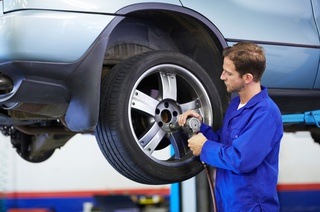 Cambio de ruedas. Un hombre que trabaja en un taller mecánico se ocupa del mantenimiento de un vehículo.